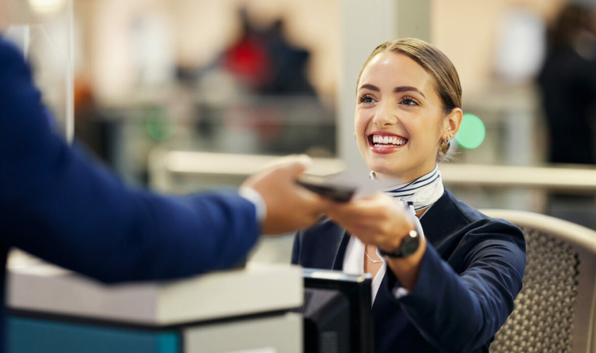 Lächelnde Frau an einem Flughafenschalter beim Check-in